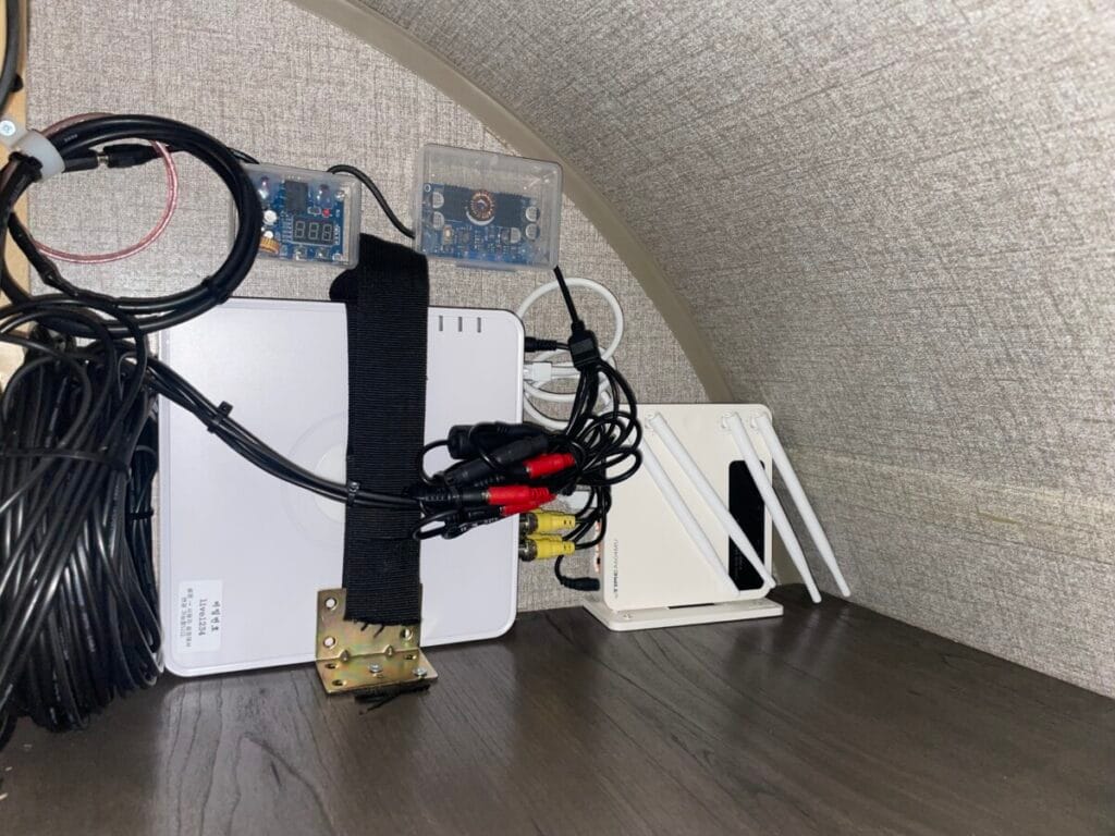 제이코 카라반 실내 수납장 안쪽에 전용 브라켓과 밴드로 단단히 고정된 4채널 CCTV 녹화기(DVR) 및 와이파이 공유기 세팅 모습